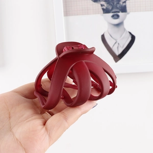 Detail of a large burgundy matte hair claw clip held by hand for size reference