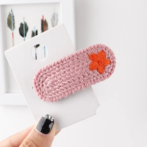 Detailaufnahme einer rosa gestrickten Haarspange mit kleiner orangefarbener Blume