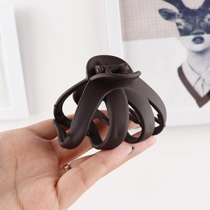 Close-up of a matte dark brown hair claw clip with multi-tooth design held in hand