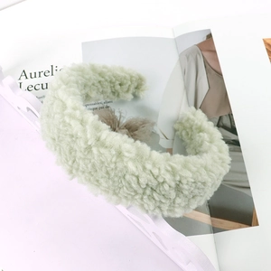 Detail of light green faux lamb wool headband with soft fluffy texture on a magazine