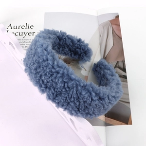 Close-up of a wide lamb wool headband in navy blue color with soft plush texture