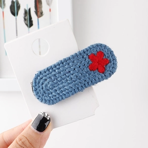 Nahaufnahme der blauen Strick-Haarklammer mit einer handgestickten roten Blume