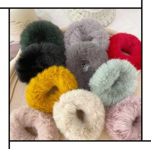 Close-up of fluffy faux fur scrunchies in various candy colors on a cream tray
