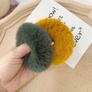 Detailed macro view of soft faux rabbit fur hair scrunchies in dark green and ginger yellow