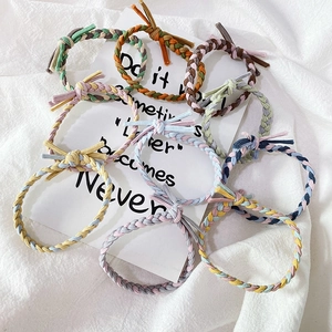 Flat lay of colorful braided hair ties set with hand-knotted details on white fabric