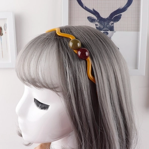 Detailansicht des gelben gewellten Stirnbandes mit Perlen auf einem Haarstyling-Modell