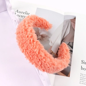 Detailed texture of thick coral orange fuzzy lamb wool headband on decorative tray