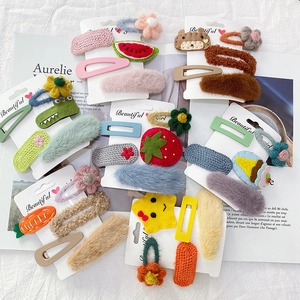 Nahaufnahme von bunten Plüsch-Haarspangen und gestrickten Frucht-Clips auf einem Magazin