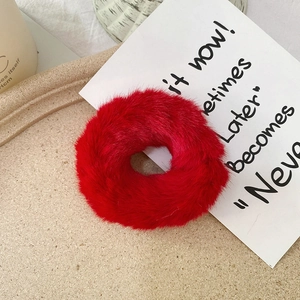Detailed view of fluffy red faux rabbit fur scrunchie on an elegant beige tray