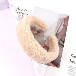Close-up of soft beige faux shearling headband showing plush curly fleece texture on a book