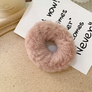 Detail of soft faux rabbit fur hair scrunchie in dusty pink on a stone tray