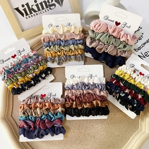 Detail view of colorful satin scrunchie sets with floral and solid patterns on cards