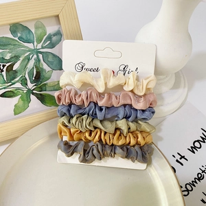 Detailed view of six colorful satin scrunchies in elegant Morandi tones on a card