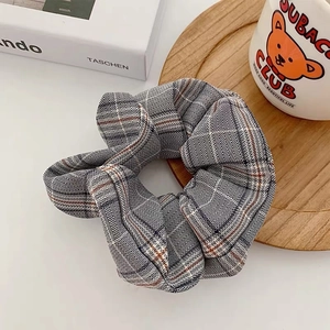 Classic grey plaid houndstooth fabric scrunchie on wooden tray with art books