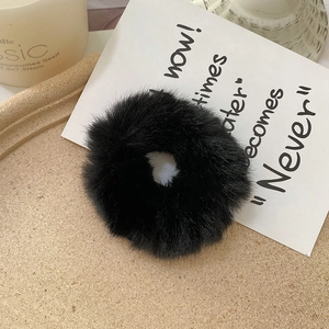 Detail of soft black faux fur hair scrunchie with plush texture on a decorative tray