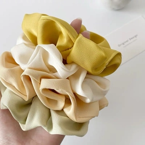 Set of four satin scrunchies in yellow, cream, champagne and green colors on a white card