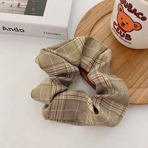 Close-up of houndstooth fabric scrunchie with dense pleats on a wooden tray