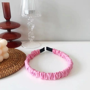 Pink pleated scrunchie headband on white table with cozy home decor background