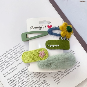 Detailansicht eines 5-teiligen Sets grüner Plüsch-Haarspangen und Strickblumen auf Karton
