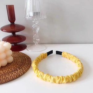 Detail of bright yellow ruched fabric headband showing soft pleated texture and black tips