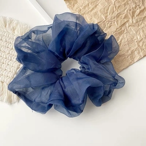 Flachbild eines marineblauen Oversized Organza Haargummis auf minimalistischem Hintergrund