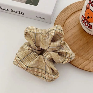 Detail of yellow houndstooth fabric scrunchie with soft pleats on a cozy wooden tray
