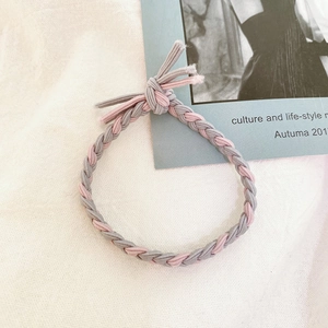 Close-up of pink and grey braided elastic hair tie on vintage aesthetic background