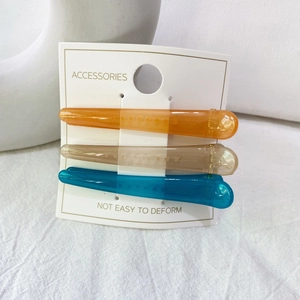Trois barrettes en résine orange, champagne et bleu présentées sur une carte