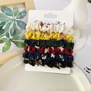 Close-up of 6-piece satin scrunchies set with leaf patterns on display card
