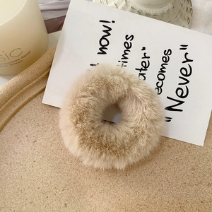 Close-up of soft apricot faux rabbit fur scrunchie on a tray with a warm aesthetic