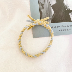 Detailed close-up of yellow and blue braided hair tie with small bow on magazine
