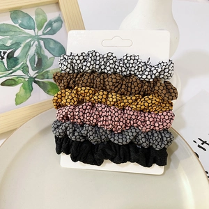 Detailed view of six textured satin scrunchies in varied colors with elegant paper tag