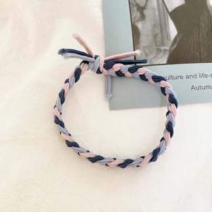 Detail of hand-woven braided hair tie with pink, navy, and grey elastic ribbon knot