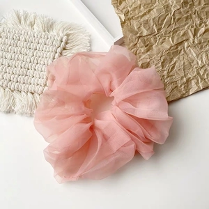 Detailstruktur des rosa übergroßen Organza-Haargummis auf dekorativem Hintergrund