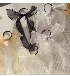 Flat lay of five organza bow hair scrunchies in cream and pastel tones with golden edges