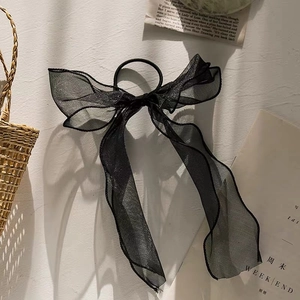 Detail of glittery black tulle bow hair tie with long ribbons and elastic hair band