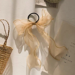 Champagne gold organza ribbon hair tie with elegant gold stitching details on a white wall