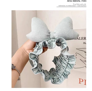 Detail of light blue plush headband featuring an oversized bow for face washing and skincare
