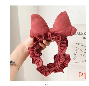 Close-up of soft burgundy bow headband with ruffled elastic band for skincare