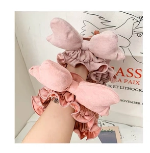 Detailed view of pink velvet bow hair ties with ruffled texture on hand