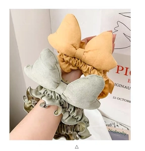 Detailed close-up of green and yellow ruffled bow scrunchies with elegant metallic pendant