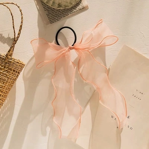 Detailed shot of soft pink organza bow hair tie with long ribbons and black elastic band