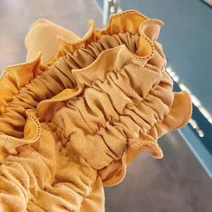 Close-up of yellow ruffled fabric texture with elastic pleated detail and stitching