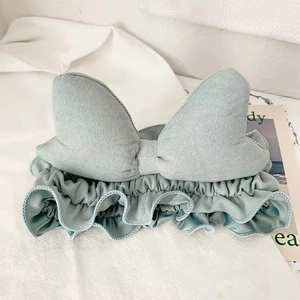 Detail of mint green fabric headband featuring a large bow on white fabric background