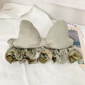 Close-up of bean green bow headband with elastic ruffled texture and soft suede fabric