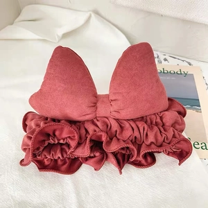 Detail of wine red suede headband featuring a large bow and ruffled trim for makeup