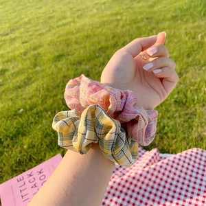 Nahaufnahme von rosa und gelben Karo-Haargummis am Handgelenk in sonniger Umgebung