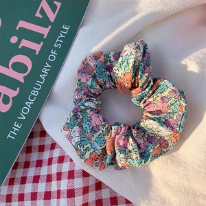Detail eines floralen Baumwoll-Scrunchie mit Vintage-Mustern und lebendiger Stofftextur