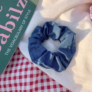 Detailansicht eines dunkelblauen Haargummis mit Denim-Textur auf einem modischen Hintergrund