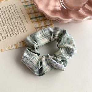 Detailed close-up of light green plaid scrunchie with soft fabric texture and ruffles